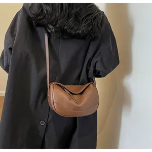 Close-up of brown litchi pattern leather crossbody bag with half-moon pleated design
