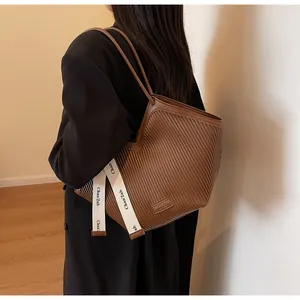Detail of brown tote bag showing textured striped pattern and decorative side strap