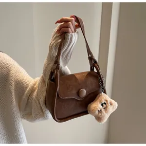 Close-up of a retro brown faux leather shoulder bag with a plush star charm
