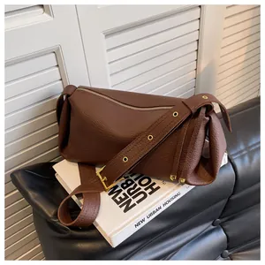Macro detail of brown lychee grain leather handbag with gold eyelets on a wide strap