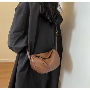 Detailed texture of brown pebble leather on a crescent crossbody bag worn by a model