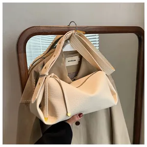 Detail of off-white lychee leather bag with wide rivet strap and gold metallic corners