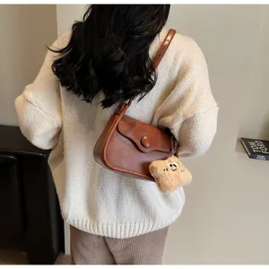 Close-up of retro brown crossbody bag with large round button and plush cloud charm