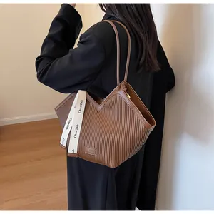 Detail of brown pleated faux leather tote bag with decorative branded ribbon and gold logo