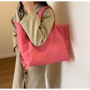 Detail of pink canvas tote bag with fringe edge design worn with a trench coat