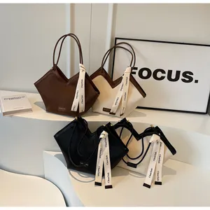 Detail view of four textured V-shaped tote bags in brown, beige, black, and ivory colors