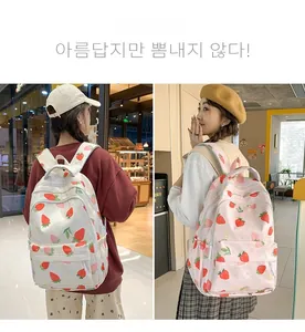 Detail view of cute strawberry print backpacks in beige and pink for students