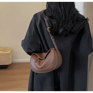 Detailed view of brown lychee grain leather crossbody bag with adjustable strap and gold hardware