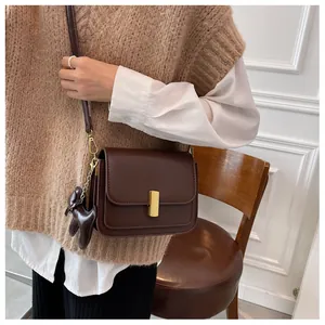 Vue détaillée du sac bandoulière en cuir marron avec boucle dorée et charm cheval