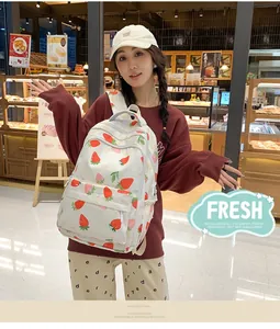 Detail of white canvas strawberry print backpack shown in a cozy bakery setting