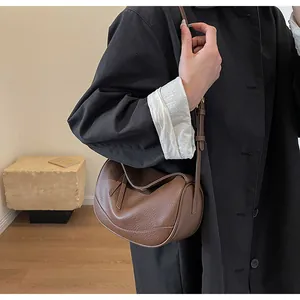 Detailed close-up of brown litchi grain leather shoulder bag with side strap buckle