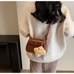 Brown crossbody bag with plush star charm shown on casual outfit in soft daylight