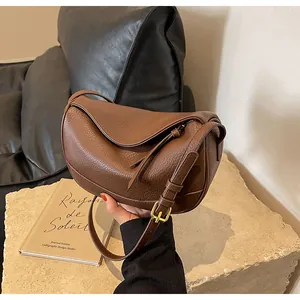 Detail of brown pebbled leather crescent bag with stylish fringe and gold hardware