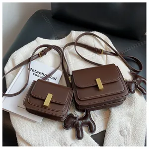 Vue détaillée de sacs bandoulière en cuir marron avec boucles dorées et breloque chien