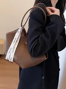 Brown accordion pleat tote bag with leather strap and decorative white silk ribbon