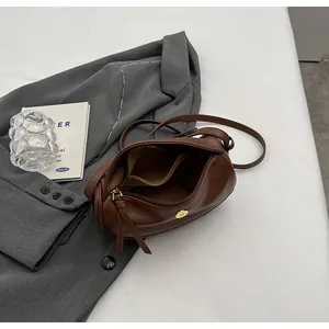 Interior view of brown lychee texture half-moon crossbody bag with zip pocket