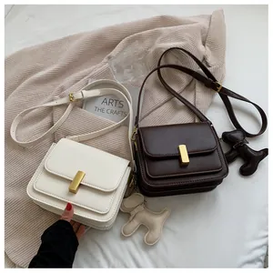 Détail du sac bandoulière carré avec fermoir doré et accessoire breloque chiot