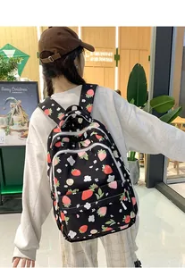 Detail of strawberry print backpack with wide shoulder straps on model in cafe