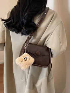 Retro brown leather crossbody bag with vintage flap and cute plush smile pendant accessory