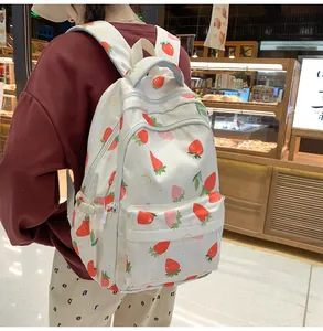 Detail of strawberry print backpack worn by a model in a cozy bakery setting