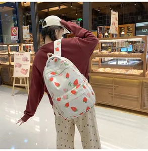 Detail of strawberry print backpack showing a large front pocket and canvas texture
