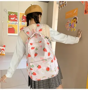 Side view of pink strawberry print backpack worn by a student in a casual setting