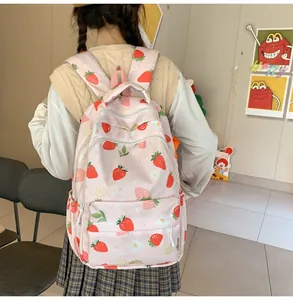 Detail of strawberry print backpack showing wide padded straps and nylon texture on model