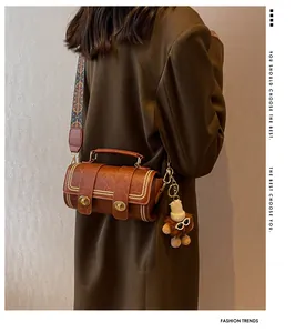 Braune Vintage-Zylindertasche mit Ethno-Gurt, Goldnieten und Plüsch-Löwen-Anhänger