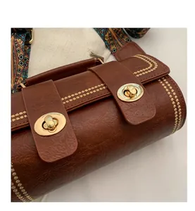 Nahaufnahme der braunen Boston-Tasche mit Lychee-Lederstruktur und goldener Stickerei