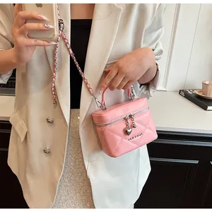 Pink quilted box bag with heart pendant and chain strap shown in a lifestyle setting