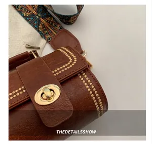 Nahaufnahme der braunen Boston Bag aus Kunstleder mit Goldschloss und Ethno-Gurt