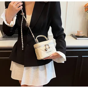 White quilted box bag with heart charms and metal handle worn with an elegant outfit