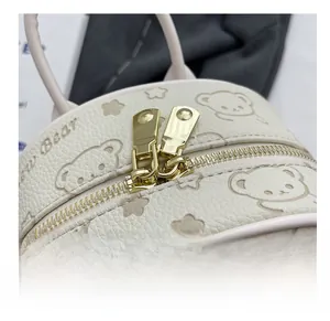 Nahaufnahme der glatten goldenen Doppelreißverschlüsse an einem beigen Bärenrucksack