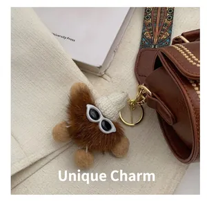 Nahaufnahme eines braunen Plüsch-Anhängers mit weißer Strickmütze an einer Vintage-Tasche