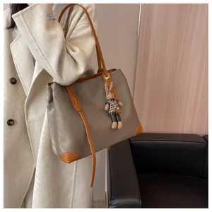 Detail of spacious nylon tote bag with orange leather straps and cute bunny charm accessory