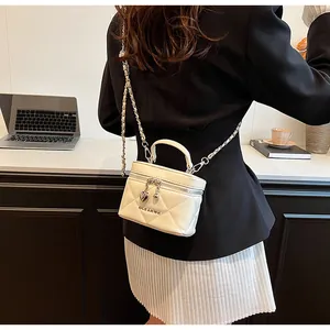 Detail of cream quilted mini box bag featuring metal chain strap and heart charm