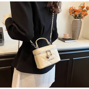 Detailed view of cream quilted vanity bag with silver chain strap and heart charm