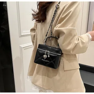 Detail showing the black quilted box bag with heart zipper pull on a beige blazer
