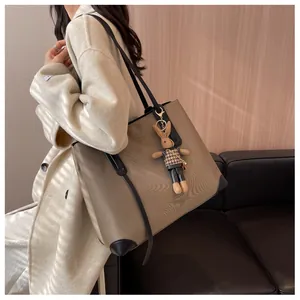 Detail of khaki tote bag with black leather trim and cute plush bunny charm