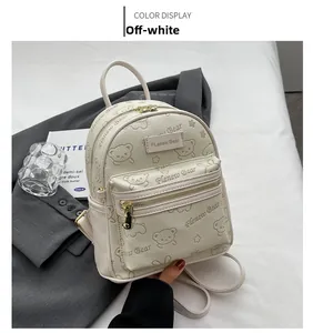 Detail eines cremeweißen Rucksacks mit süßem Bärenmuster und goldenem Reißverschluss