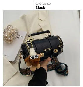 Detail der schwarzen Boston-Tasche mit Goldnieten, Plüschbär und buntem Web-Schultergurt