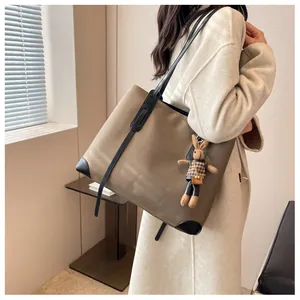 Detail of khaki tote bag with black leather straps and cute brown bunny charm accessory