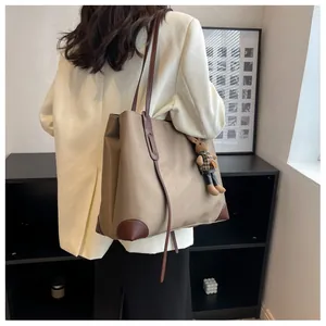 Detail of large khaki tote bag with dark brown straps and a cute rabbit charm accessory