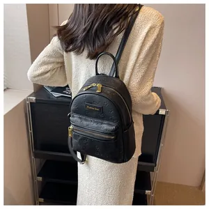 Detail eines schwarzen Lederrucksacks mit Bären-Prägung und goldenen Metallelementen