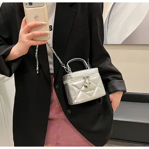 Detail of silver quilted mini box bag with metallic finish and heart charm pendant