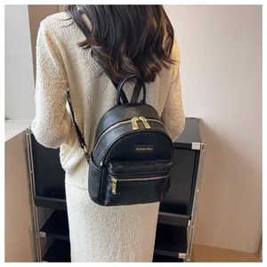 Detail eines schwarzen Mini-Rucksacks mit geprägtem Bärenmuster und goldenem FLenew Bear Logo
