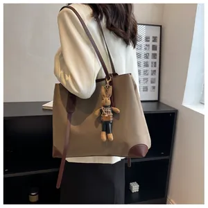 Detail of khaki nylon tote bag with brown leather trim and cute rabbit doll keychain charm