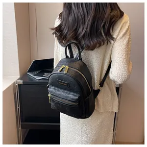 Detail eines schwarzen Rucksacks mit Bärenmuster und Goldplakette am Modell