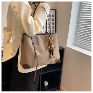 Detail of khaki tote bag with brown leather handles and cute bunny charm accessory