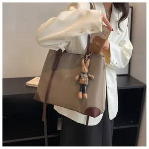 Macro shot of minimalist earth-tone tote bag with brown leather corners and plush rabbit charm